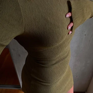 A-DSGN klänning - Långärmad klänning med kroppsformande veckat tyg i olivgrön/khaki färg. Super fin köpt på Plick och av mig endast använd 1 gång och ser ut som ny! Materialet är tunt och stretchiga så passar bra nu på sensommar och närmare höst/vinter. 