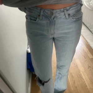 Midwaist straight jeans - Ljusblåa straight jeans med hål vid ena knät. 