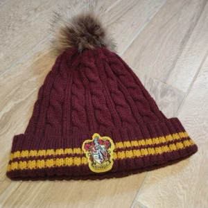 Harry Potter Gryffindor Mössa  - En Harry Potter Gryffindor Röd Gul Mössa. Jättefin och nästan i nyskick. Använd bara ett väldigt få antal gånger. Sömmen har dock gått lite av, kolla sista bild. Mycket skön.