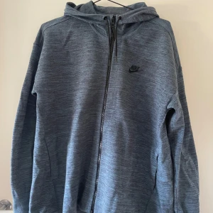 Grå hoodie från Nike - Säljer en blågrå hoodie från Nike i storlek L. Den har en dragkedja framtill och en bekväm huva. Perfekt för vardagsbruk eller träning. Den är i bra skick och supermjuk!