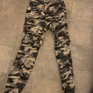 Camouflage cargobyxor från Madlady - Snygga camouflage cargobyxor från Madlady i storlek S. Byxorna har flera praktiska fickor och en cool militärinspirerad look. Perfekta för en avslappnad och trendig stil. Användna 1 gång 