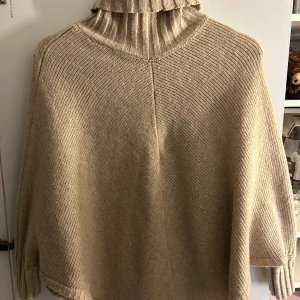 Beige stickad poncho - Säljer en mysig beige stickad poncho med polokrage. Köpt tidigare från Vinted, aldrig använd. Står inget märke på plagget. Pris kan diskuteras💕