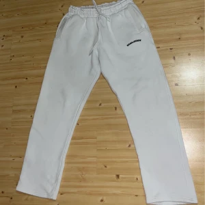 Vita mjukisbyxor från Smalldox - Säljer ett par vita mjukisbyxor från Smalldox. Byxorna har en elastisk midja med snörning och två sidofickor. Perfekta för en avslappnad stil.