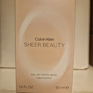 Calvin Klein Sheer Beauty Eau de Toilette.  Oanvänd  - Calvin Klein Sheer Beauty är en elegant eau de toilette med en volym på 50 ml. Förpackningen har en mjuk beige ton med subtila detaljer. Perfekt för den som söker en sofistikerad och fräsch doft. Oanvänd 