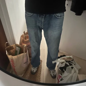 Hope byxor 34’’ - Säljer ett par klassiska blå jeansbyxor med en avslappnad passform. Byxorna har en rak stil och är perfekta för en casual look. De har traditionella fem fickor och en knappgylf.