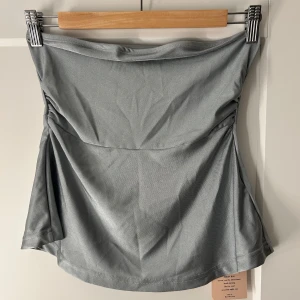 Topp - Säljer denna snygga Bandeau toppen i en jättefin grön/blå färg. Toppen är endast testad