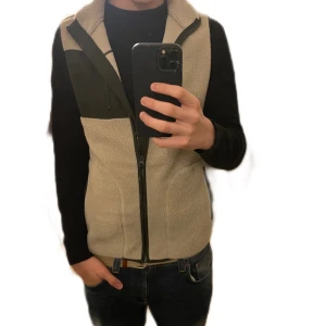 Beige fleeceväst  - Säljer en snygg beige fleeceväst, med svarta detaljer. Västen har en dragkedja framtill och praktiska fickor. Skick 10/10 tar gärna byten