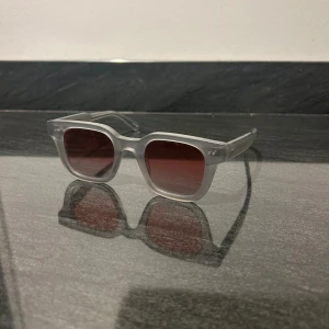 Transparenta solglasögon från Chimi - Snygga solglasögon från Chimi med fyrkantig form och rödtonade linser. Limeted edition. Dem är endast använda vid 1 tillfälle som visas på bild 4. Dem har inga skador eller skavanker. Perfekta för att ge en cool touch till din stil. Kommer självklart med original låda samt putsduk. Nypris ligger på 1500kr då jag köpte dem från Chimi och inte från återförsäljare. Pris kan diskuteras, samt byte mot andra solglasögon eller annan vara kan diskuteras (Skriv till mig i meddelanden). 