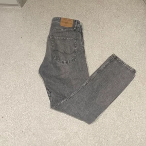 Grå jeans från Jack & Jones - Säljer ett par grå jeans från Jack & Jones i loose fit. De har en klassisk femficksdesign. Perfekta för en avslappnad stil.