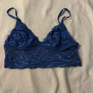 Blå spets bralette/linne från Shein - Säljer en snygg blå spets bralette/linne från Shein. Den har justerbara axelband och ett vackert spetsmönster som ger en romantisk känsla. Perfekt för att bära under en topp eller som den är.