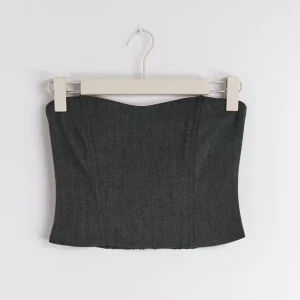 Grå tubtopp - Helt ny med prislapp grå tubtopp från Ginatricot🩶 Nypris 399kr Toppen är axelbandslös och har en elastisk baksida för bättre passform. Bustieri tweed med smock i ryggen och har en hjärtformad ringning.