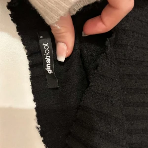 Svart ribbad tröja från Gina Tricot - Säljer en stilren svart ribbad tröja från Gina Tricot. Tröjan har långa ärmar och är perfekt för kyligare dagar. Den är både bekväm och lätt att matcha med olika outfits. tröjan är svart men såg grön ut på bilden skit snygg säljer för använder ej