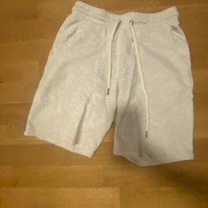 Vita shorts med snörning - Snygga och bekväma vita shorts med elastisk midja och snörning. Perfekta för en avslappnad stil. De har en enkel design med fickor på sidorna.