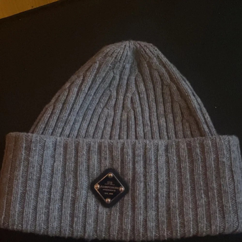 Snygg grå ribbad mössa från J.Lindeberg med en stilren logotyp framtill. Mössan har nästan aldrig använts och är som ny. . Asusteet.