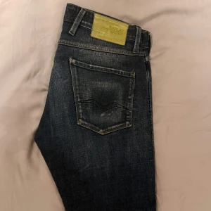 Mörkblå jeans från Replay - Snygga mörkblå jeans från Replay. Modellen heter anbass slim och de har en gul/grön backtab som är lite unik. Även en snygg tvätt. De är i nyskick 9/10. Midja=32 längd=32.  Priset är ej hugget i sten.