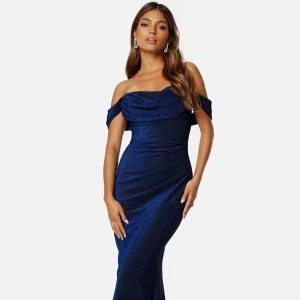 Mörkblå glittrig långklänning - Mörkblå glittrig långklänning med offshoulder-design. Klänningen har en figurnära passform och en vacker drapering över bysten. Klänningen är väldigt bekväm och har ett stretchigt material. Tvättråden är endast handtvätt. Klänningen har använts en gång och passade perfekt på mig som skiftar mellan XS, S på sånna här typer va klänningar. Skriv gärna om den finns frågor eller andra prisförslag💕💕 (ord. pris: 1199 kr