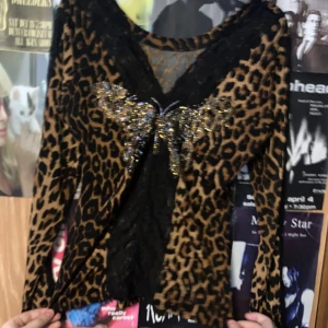 Leopardmönstrad tröja med paljettdetaljer - Snygg leopardmönstrad tröja med glittrande paljettdetaljer framtill. Tröjan har långa ärmar och en djup v-ringning med spetskant. Passar fint och e skön att ha på.