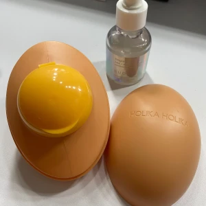 Smooth Egg Skin Cleansing Foam och Tingle Bell Exfoliating Mask - Säljer en innovativ ansiktsrengöring från Holika Holika, formad som ett ägg, perfekt för att förbättra hudens lyster och elasticitet. Inkluderar även Budgie Tingle Bell exfolierande mask med AHA och BHA för en djup rengöring och uppfräschning av huden. Ca 70%-80%  kvar. 