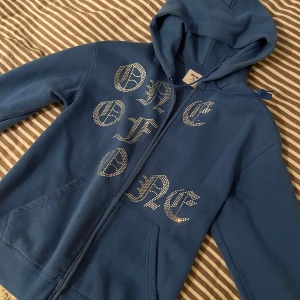 Blå hoodie från One of One - Säljer en blå hoodie från One of One med strassdetaljer. Aldrig använd, nypris ca 1000
