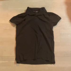 Svart piké från 157 - Säljer en svart t-shirt från 157 i storlek M. Den har en klassisk design med korta ärmar och rund hals. Perfekt för en enkel och stilren look.