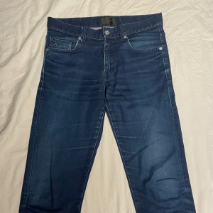 Blå jeans från J.Lindeberg - Säljer ett par snygga blå jeans från J.Lindeberg Perfekta för en stilren look. Dem är slimfit och storleken 31/32, men passar antagligen om du är lite mindre än det också. Skriv gärna vid frågor!👍🏼😁
