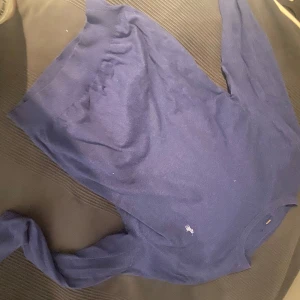 Blå långärmad tröja från Ralph Lauren - Säljer en stilren blå långärmad tröja från Ralph Lauren. Tröjan har en liten broderad logotyp på bröstet och är perfekt för en avslappnad look. Passar bra till både jeans och chinos.