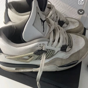 Nike Air Jordans i vit och grå - Säljer ett par klassiska Nike Air Jordans i vit och grå färg. Skorna har snörning och en ikonisk Jumpman-logga på tungan och hälen. Perfekta för sneakerheads som älskar retrostil.