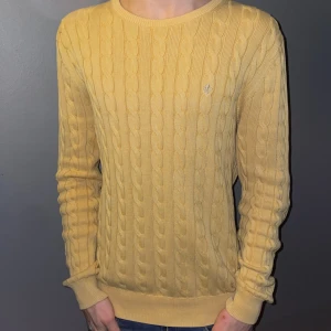 Gul stickad tröja från Morris - Säljer en snygg gul stickad tröja från Morris med kabelstickat mönster. Tröjan har långa ärmar och en rund halsringning. Perfekt för att hålla sig varm och stilren. Pris kan diskuteras vid snabb affär!