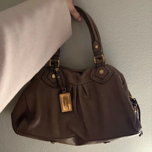 Marc Jacobs väska  - Säljer denna superfina väskan från By Marc Jacobs i en beige färg. I mycket fint skick😊🙌🏼Köpte den för 2600 kr🥰Kommer även med ett längre band också🫶🏼