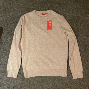 Beige tröja från RYVLS - Säljer en stilren beige tröja från RYVLS. Tröjan har en klassisk rund hals och långa ärmar. Den är stickad i ett väldigt skönt material. Helt ny med prislapp. Köptes för 500kr