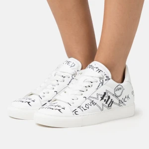  Zadig & Voltaire skor - Snygga vita sneakers från Zadig & Voltaire med svart text och grafiska detaljer. Skorna har snörning och en klassisk siluett. Använda cirka 2 gånger bara. Köpta för 2500kr💞