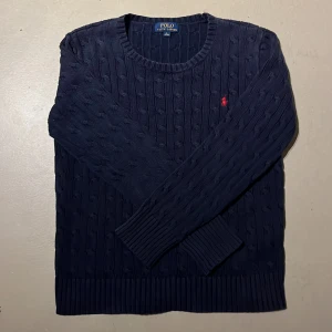 Ralph lauren tröja  - säljer nu denna snygga kabelstickade Ralph lauren tröjan i storlek 14-16, skulle säga att den passar bäst runt 165 men allt runtomkring funkar också bra. Den är i nyskick, syns knappt att den är använd. Inga defekter överhuvudtaget. Självklart äkta. 