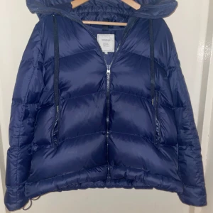 Mörkblå pufferjacka från Boomerang - Säljer en snygg mörkblå pufferjacka från Boomerang. Jackan har en dragkedja framtill och en stor huva för extra värme. Perfekt för kyliga dagar och ger en stilren look. 🧥 Dm för mera bilder och information. 😄Nypris är 6900.