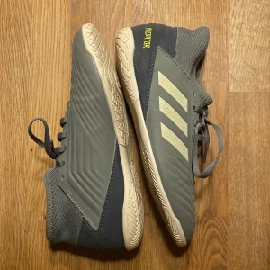 Gröna Adidas Predator inomhusskor - Säljer ett par gröna Adidas Predator inomhusskor med snörning och ljus sula. Stilren design med  Adidas- logga på sidan  och  'PREDATOR - text  i neon  på hälen. Perfekta för inomhusfotboll. Skorna är i mycket bra skick . BARA ANVÄND EN GÅNG 