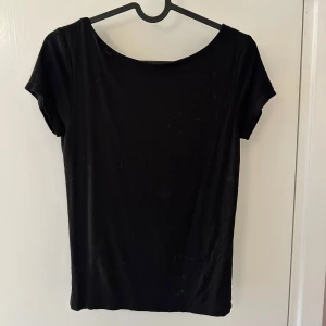 Svart kortärmad topp med urringning i ryggen från Gina tricot! - Snygg svart topp med korta ärmar och djup urringning i ryggen från Gina tricot!🖤