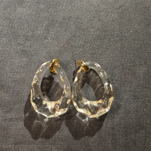 Transparenta örhängen med gulddetaljer - Säljer ett par snygga transparenta örhängen med guldfärgade detaljer. De har en unik, oregelbunden form som ger en modern och stilren look. Perfekta för både vardag och fest! 🥳