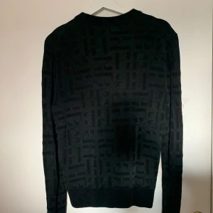 Svart mönstrad tröja Hugo Boss - Säljer en stilren svart tröja med ett diskret mönster. Perfekt för både vardag och fest. Tröjan har långa ärmar och en normal passform. Den är gjord i ett mjukt material som känns skönt mot huden. Passar perfekt till höst- och vintergarderoben.