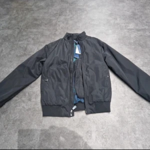 Svart jacka från Polo Ralph Lauren - Säljer en snygg svart bomberjacka från Polo Ralph Lauren i storlek XS. Jackan har en klassisk design med dragkedja och ribbade muddar. Perfekt för höst och vår! Skick 10/10