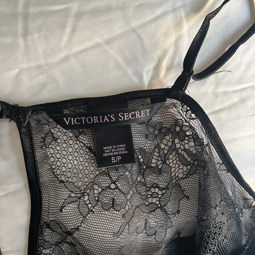 Säljer ett elegant svart sidenlinne från Victoria's Secret. Det har tunna axelband och vacker spetsdetalj vid halsringningen. Perfekt för en kväll ute eller som ett lyxigt lager under en kavaj. 🖤. Toppar.