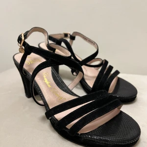 DASIA klackskor🖤 - Svarta klackskor i mocka och glansigt material vid tårna, vilket är väldigt fint när skon är på! Mocka-remmarna korsas över foten. Spänne runt hälen med guldig detalj. Klacken är 8 cm och enkla att gå i, sulan är dessutom väldigt mjuk och skön. 🖤