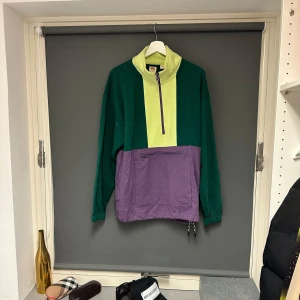 Skön tröja från Levi's - Säljer en cool och färgglad tröja från Levi's i storlek S. Den har en unik färgkombination av grönt, lila och lime med en praktisk dragkedja framtill. Perfekt för att sticka ut i mängden! Enbart använd vid ett fåtal tillfälle på sparsamt sätt så den är som i nyskick. 