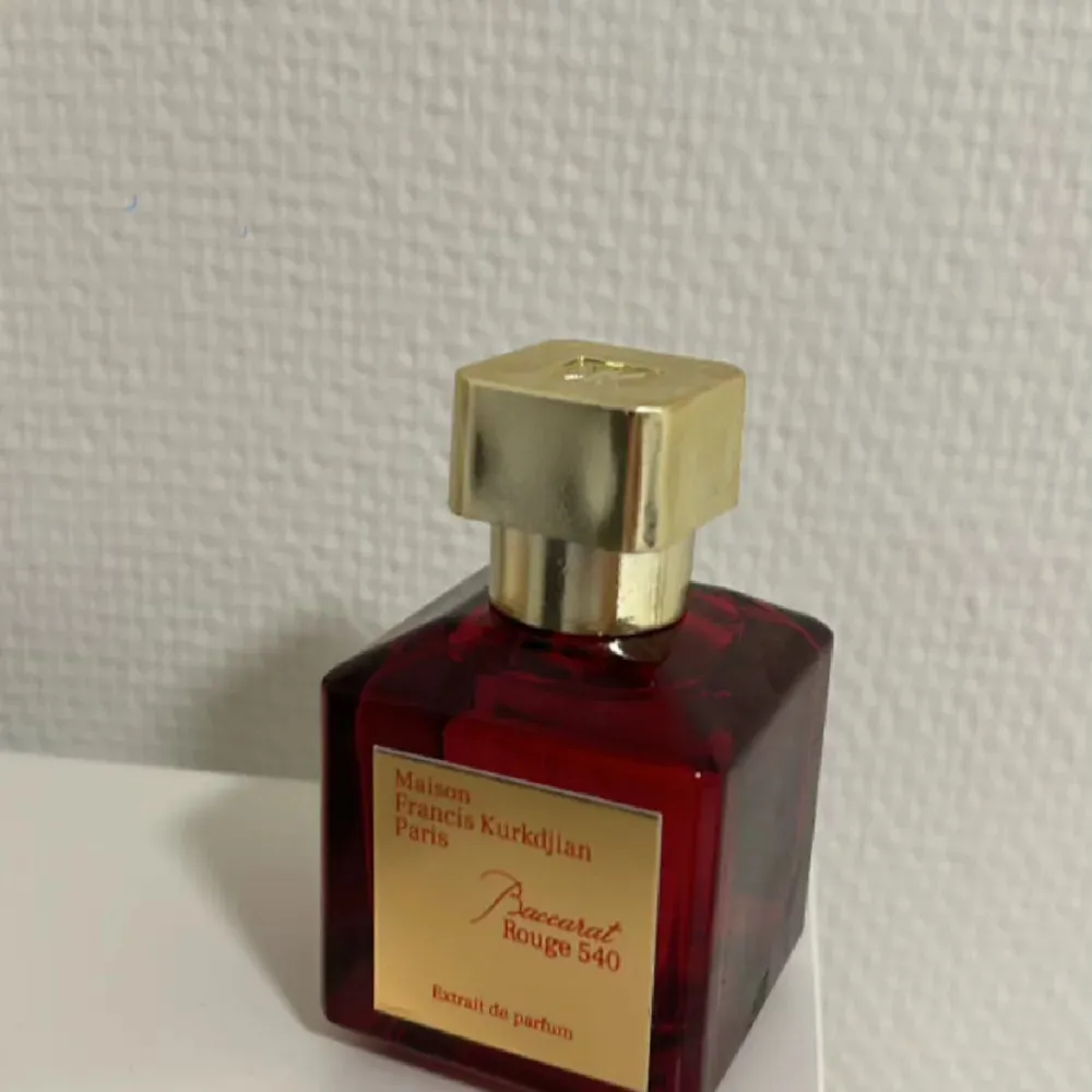 Säljer en lyxig parfymflaska av Maison Francis Kurkdjian, Baccarat Rouge 540 Extrait de Parfum. Flaskan är elegant och djup röd med en gyllene etikett och kork. Perfekt för den som vill ha en exklusiv doftupplevelse. Passar både till vardags och speciella tillfällen.. Parfym.