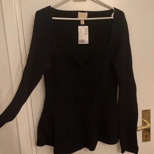 Svart ribbad tröja från H&M - Säljer en stilren svart ribbad tröja från H&M. Den har en v-ringad design och långa ärmar, perfekt för både vardag och fest. Tröjan är i storlek M och passar bra till höst- och vintergarderoben. Nypris 499 SEK, men säljer den billigare. Hör av dig vid intresse!