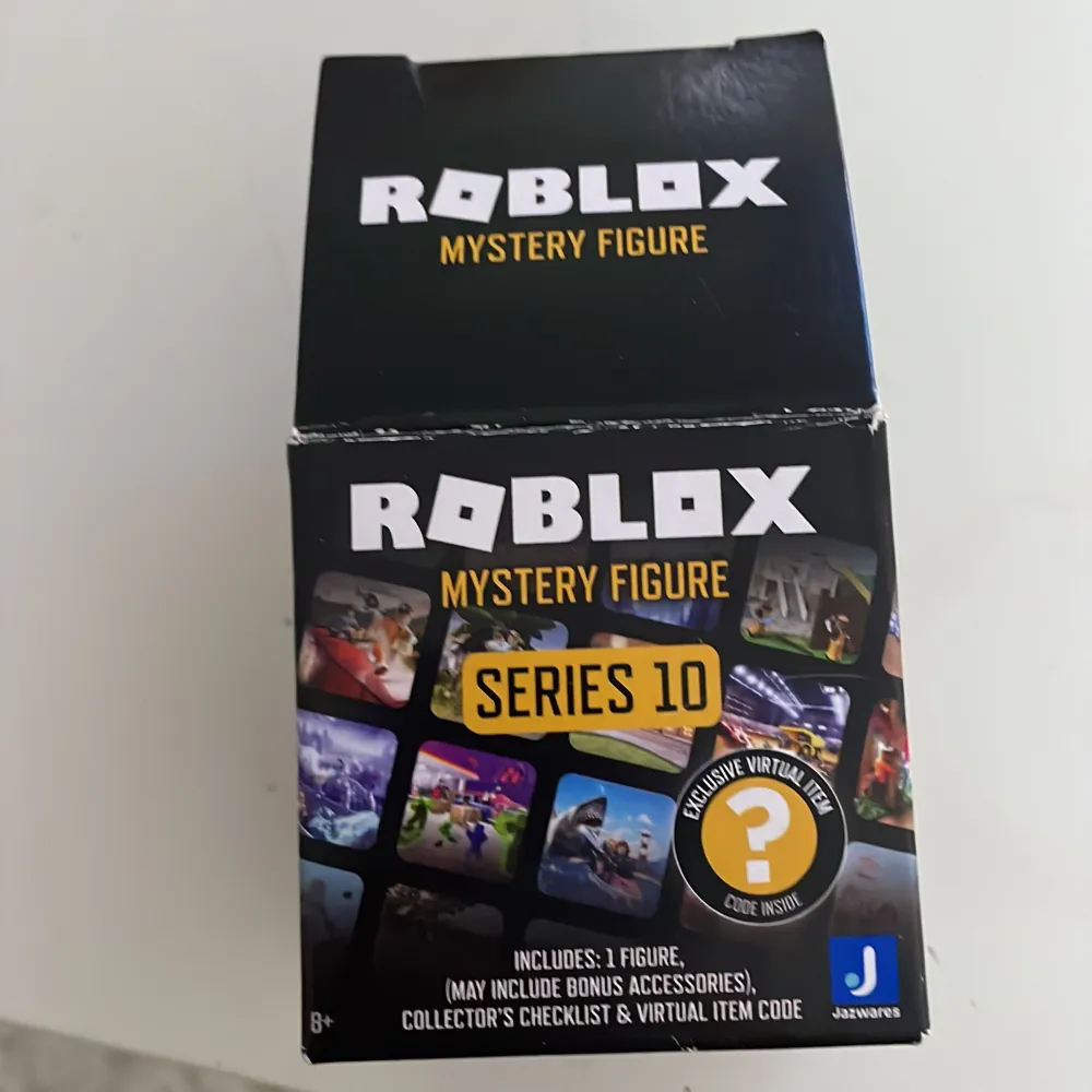 Cool Roblox-figur från Mystery Figure Series 10. Den har en unik design med ett grått kostymtryck och ett huvud som ser ut som en svart boll med röda prickar. Perfekt för samlare eller som en rolig leksak för . Övrigt.