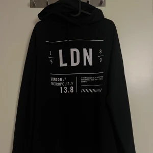 Svart hoodie med tryck  - Säljer en svart hoodie med coolt LDN-tryck på framsidan. Från New Yorker i storlek XL. Perfekt för en avslappnad stil och passar bra till både jeans och joggers. Den har långa ärmar och en bekväm huva med dragsko. Perfekt för höst och vår! Denna är endast provat men fel storlek. 