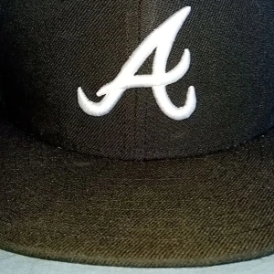 Svart keps från New Era - Säljer en svart keps från New Era, modell 59FIFTY. Den har en vit broderad bokstav 'A' på framsidan och MLB-loggan baktill. Perfekt för både vardag och sportiga tillfällen. Kepsen är i bra skick och redo för nya äventyr!