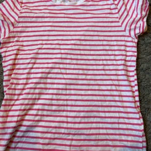 Rosa och vit randig t-shirt från FSBN Sister - Säljer en söt och casual rosa och vit randig t-shirt från FSBN Sister. Perfekt för sommardagar eller avslappnade tillfällen. T-shirten är kortärmad och gjord i mjukt bomullsmaterial. Den har en normal passform och är i bra skick. Perfekt för en enkel och stilren look! 🌸