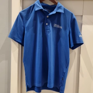 Blå pikétröja från Oscar Jacobson - Säljer en snygg blå pikétröja från Oscar Jacobson i storlek S. Tröjan har korta ärmar och en klassisk krage med knappar. Perfekt för både vardag och lite finare tillfällen. Den är i bra skick och har en stilren design med logotypen broderad på bröstet. Liten tråd på sidan av magen som knapp syns.