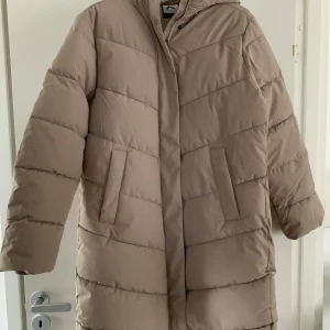 Vinterjacka i nyskick i polyseter  - Vinterjacka i nyskick i polyester. Varm och skön. Längd från axel till nederkant 90 cm bröstmått 55 cm. 
