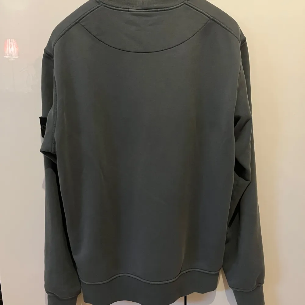 Säljer en stilren grå sweatshirt från Stone Island. Den har en klassisk rund hals och långa ärmar. På vänster ärm finns det ikoniska Stone Island-märket. Perfekt för en casual look eller att bara mysa i. Passar till alla säsonger! Skick 9/10! Ända defekt ser ni på bild 5. Köpt på NK stockholm, kvitto finns. Nypris ca 3000kr.. Neuletakit & Villapaidat.